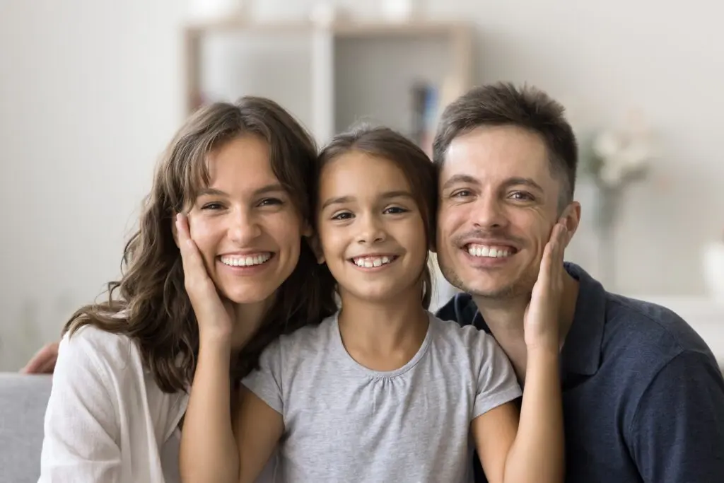 happy loving family flashing smiles, little girl in between parents