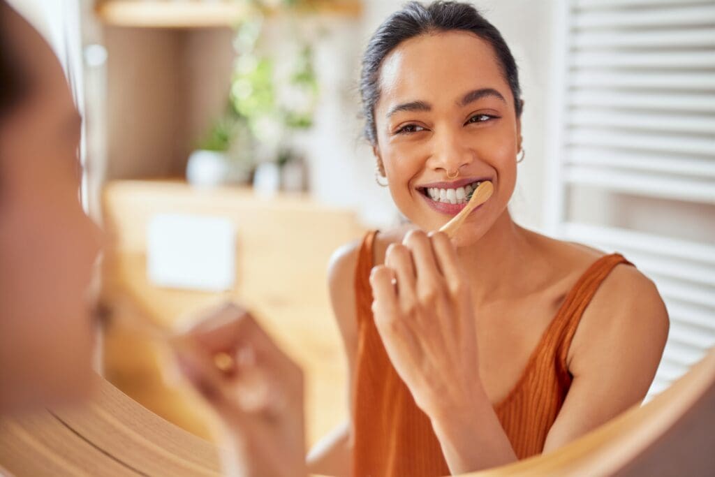 smiling young woman brushing her teeth and gums