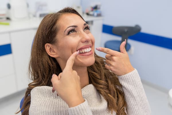 smiling woman pointing to her bonded tooth