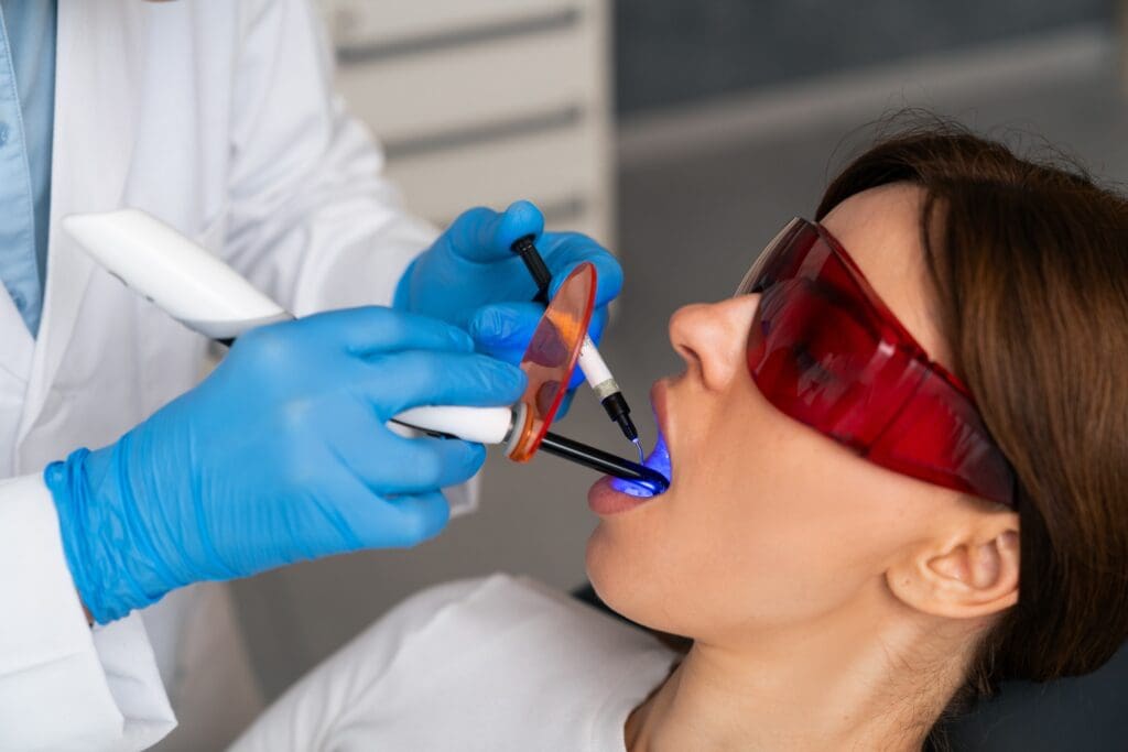 doctor in blue gloves using dental laser on female patient